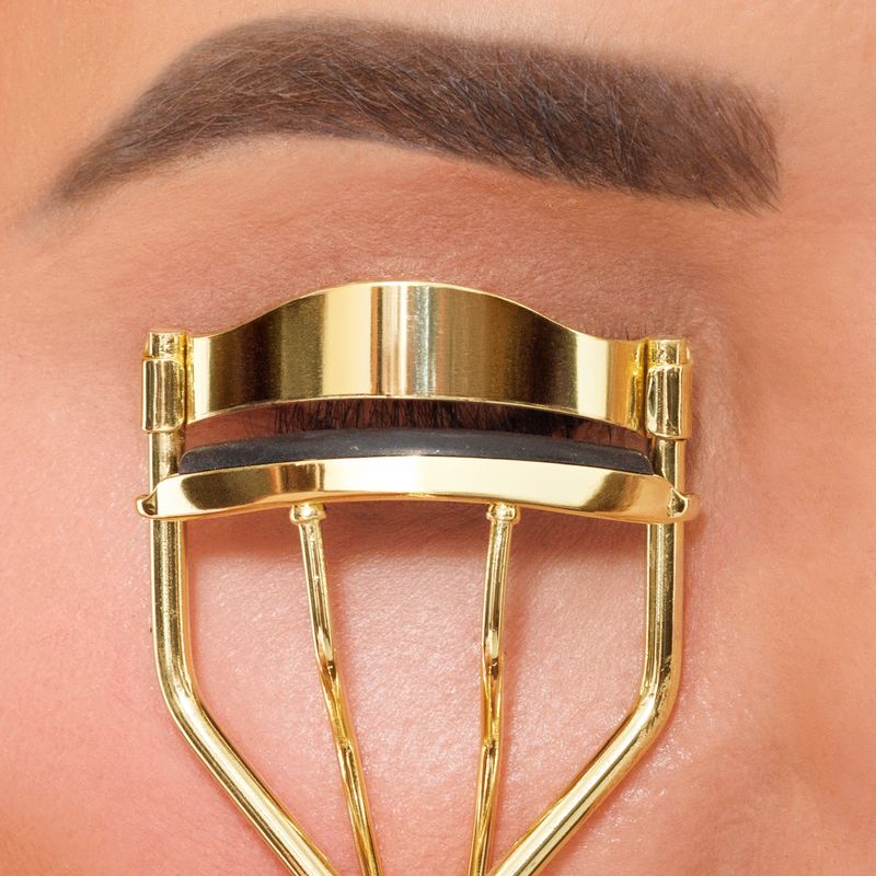 Gold eyelash curler on a person's eyelashes