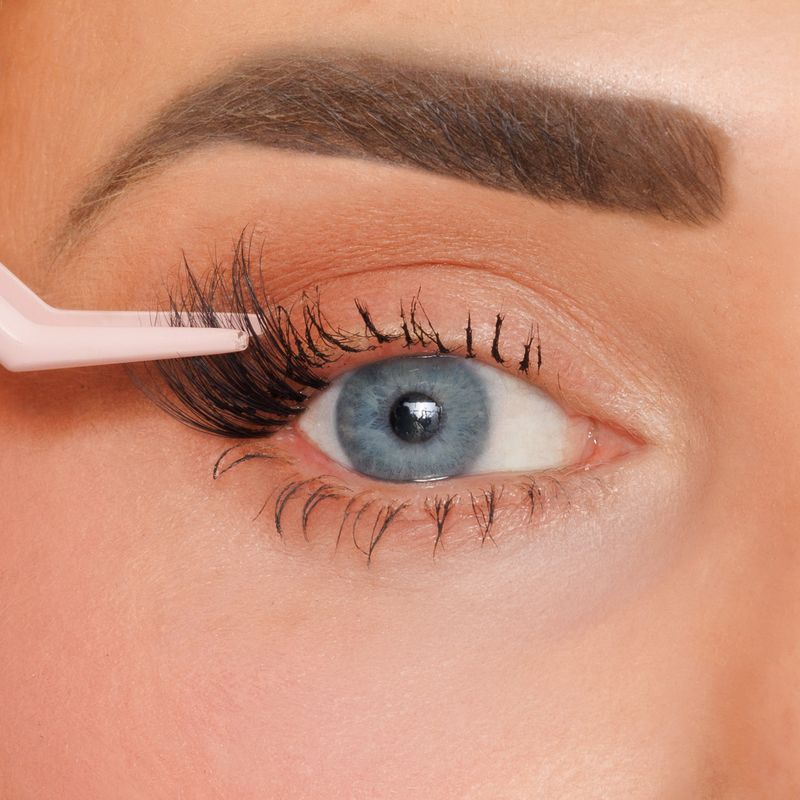 Person applying eyelash extensions with a tool