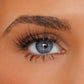 Close-up of a person's eye with long, dark, curled eyelashes and a neatly shaped eyebrow on warm tan skin.
