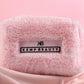 Folded pink Kemp Beauty travel bag with branded tag