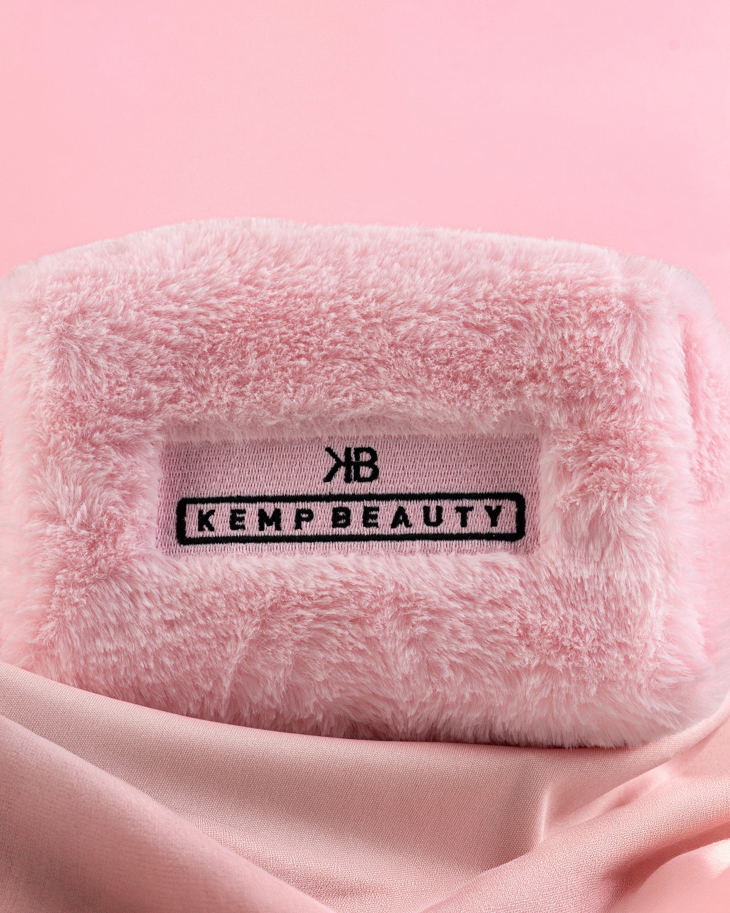 Folded pink Kemp Beauty travel bag with branded tag