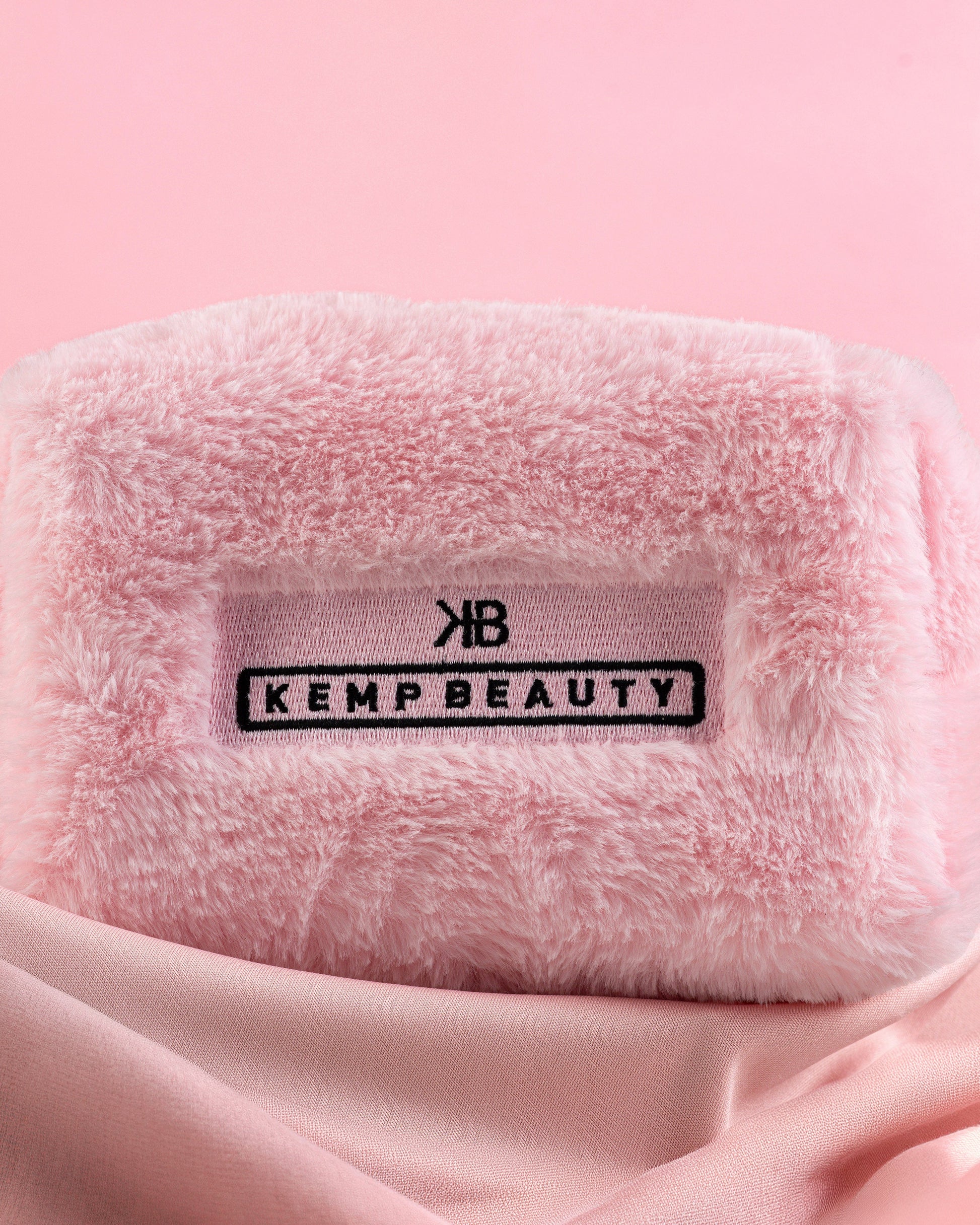 Folded pink Kemp Beauty travel bag with branded tag