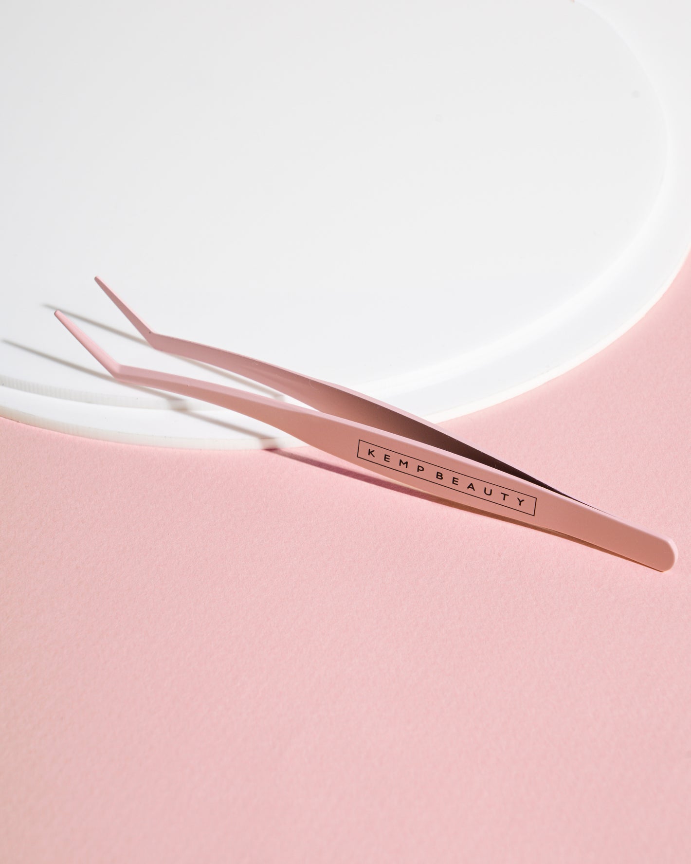 Eyelash curler and applicator tweezer tool included in the kit, styled on satin