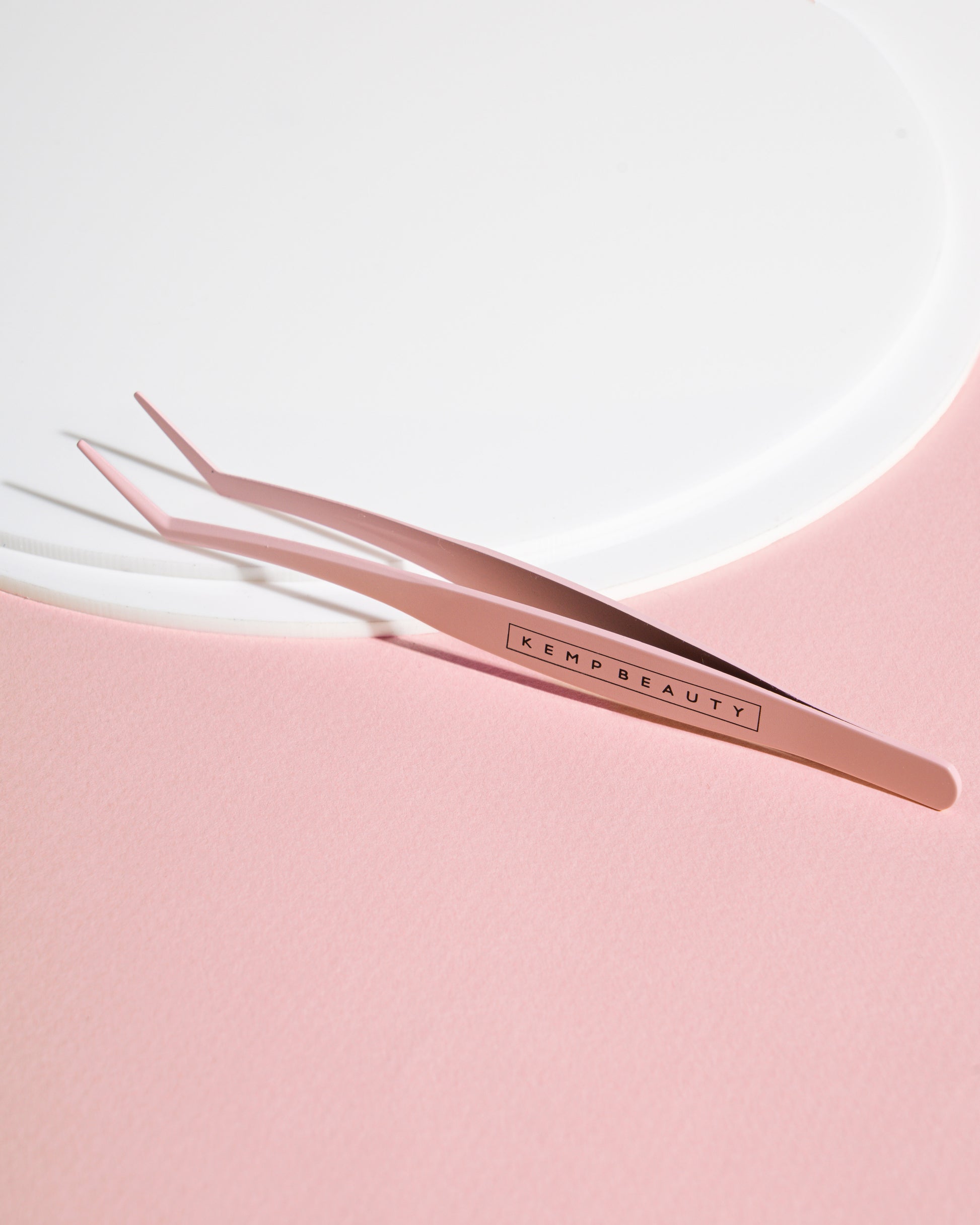 Eyelash curler and applicator tweezer tool included in the kit, styled on satin